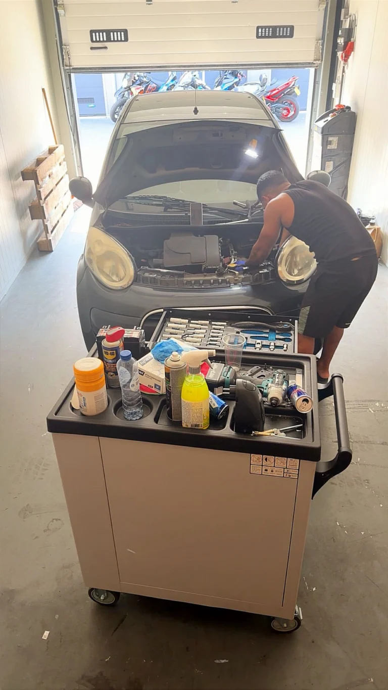 Monteur van Mechanics 4 Service werkt aan een motor, met gereedschapswagen ernaast