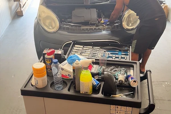 Monteur van Mechanics 4 Service werkt aan een motor, met gereedschapswagen ernaast