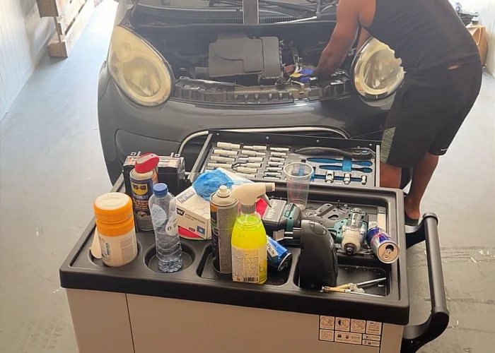 Monteur van Mechanics 4 Service werkt aan een motor, met gereedschapswagen ernaast
